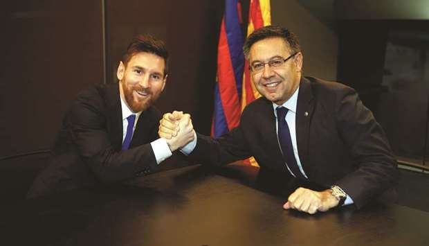 Barcelonau2019s Argentine superstar Lionel Messi poses with FC Barcelona president Josep Maria Bartomeu during the signing of his new contract in Barcelona yesterday.