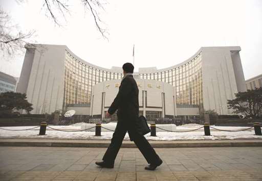 A man walks past the headquarters of Chinau2019s central bank in Beijing. The new rules underscore Beijingu2019s determination to reduce risks and further standardise the countryu2019s financial markets.