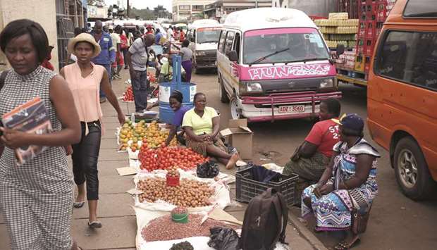 Locals walk past street vendors selling vegetables in Harare yesterday.