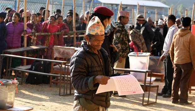 A Nepali voter examines a ballot papers before casting his vote at a polling station during the general election at Chautara