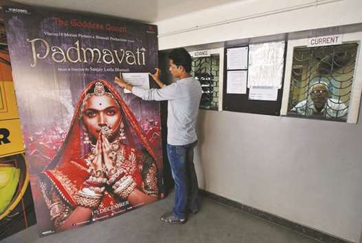 A worker tapes a message in support of the release of Padmavati on its poster in a cinema hall in Kolkata yesterday.