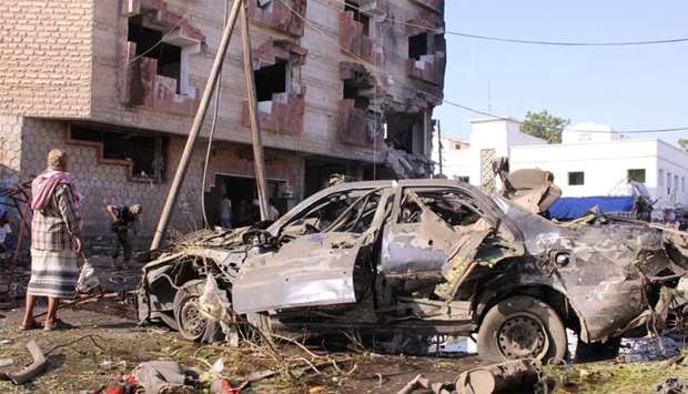 Man stands by a damaged car at the site of a car bomb attack outside the Finance Ministry offices in the southern port city of Aden, Yemen