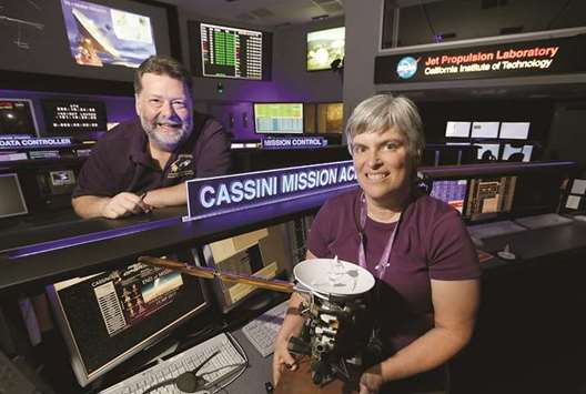 BIDDING ADIEU: Jo Pitesky, right, Cassini project scientist/engineer holds a model of the Cassini craft and Todd Barber, lead propulsion engineer, in the Mission Control Center at Jet Propulsion Laboratory in Pasadena, California.