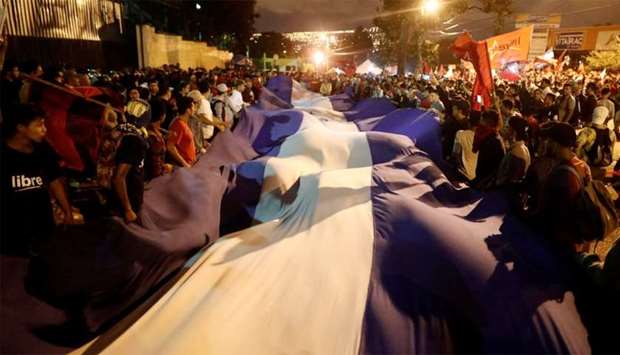 Supporters of Nasralla hold a Honduran flag while they wait for the official presidential election results in Tegucigalpa