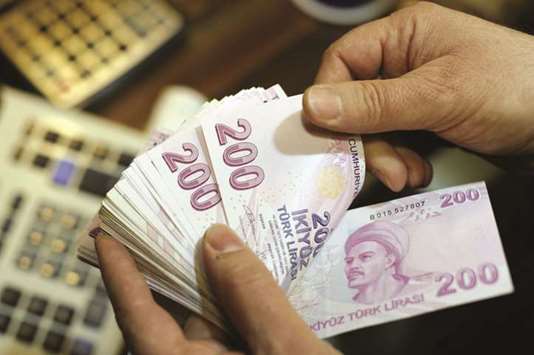 A money changer counts Turkish lira bills at a currency exchange office in Istanbul (file). The central bank raised its year-end inflation estimate to 9.8% from 8.7% on November 1, driven by the depreciation in the lira and higher oil prices.