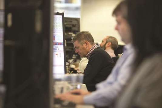 Traders study information on trading screens at ETX Capital in central London (file). The benchmark FTSE 100 equities index closed down 0.9% yesterday.