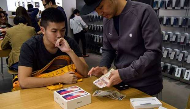 An employee counts cash at an Apple store as a customer buys two iPhone X devices in Hong Kong on Friday.