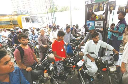Customers wait to buy petrol at a fuel station in Karachi.