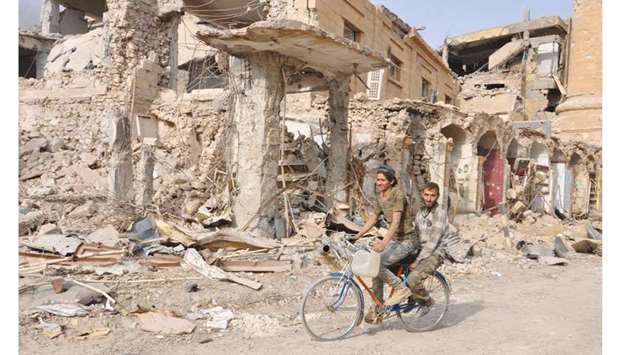 Men ride a bicycle in the eastern Syrian city of Deir Ezzor during a military operation by government forces against Islamic State militants.