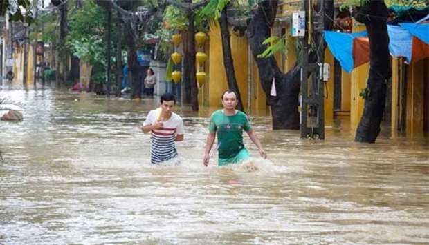 Local residents wade through flood waters in the central tourist town of Hoi An on Monday following heavy rains caused by Typhoon Damrey.
