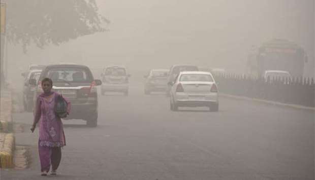 An Indian woman walks on a road during heavy smog in New Delhi on Tuesday.