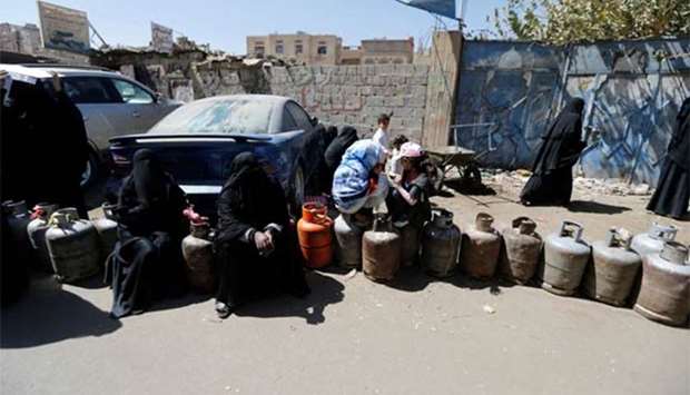 Women sit on cooking gas cylinders lined up outside a gas station amid supply shortage in Sanaa on Tuesday.