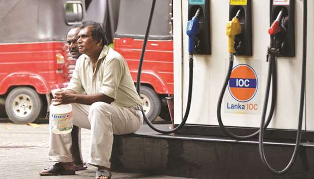 Commuters wait at a fuel station in Colombo yesterday.