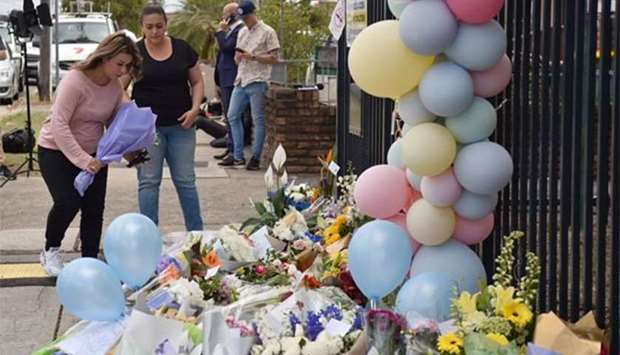 Women lay a floral tribute outside the Banksia Road Public School on Wednesday, a day after a car crash killed two pupils inside the school's premises in Sydney's west.