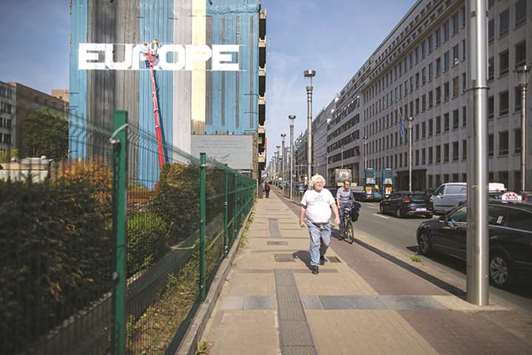 Pedestrians walk by on the street next to the European Commission and the Europa buildings in Brussels. The European Commissionu2019s proposal aims to curb greenhouse gases from transport as part of a drive to cut emissions by at least 40% below 1990 levels by 2030.
