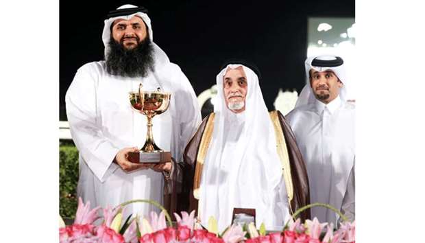 Yousef bin Ahmed al-Kuwari (centre) presents the trophy to ownersu2019 representative Mishal al-Attiyah (left) after Rassan won the Owners Cup at the Qatar Racing and Equestrian Club yesterday. PICTURE: Juhaim