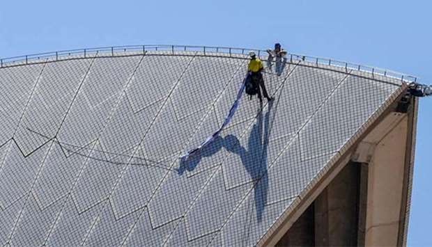 A policeman talks with an abseiling protester as he holds a banner on top of the Sydney Opera House on Thursday.