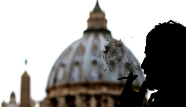 A man smokes a cigarette in front of St. Peter Square, in Rome
