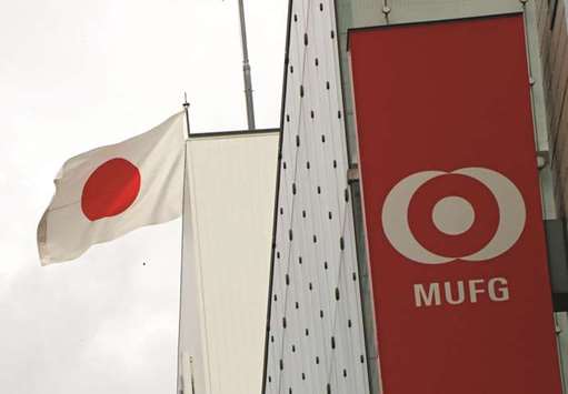 Japanu2019s national flag is seen behind the logo of Mitsubishi UFJ Financial Group at its bank branch in Tokyo. MUFG, through its core unit Bank of Tokyo-Mitsubishi UFJ, intends to buy Danamon shares from Singapore state investor Temasek Holdings, a major shareholder, said two sources, who declined to be named as the talks were not public.