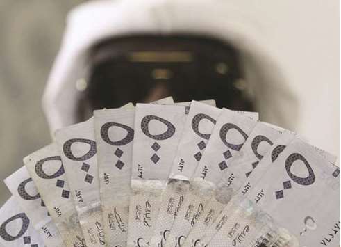 A Saudi man poses with Saudi riyal banknotes at a money exchange shop in Riyadh. If the Saudi committee were to try to retrieve all the revenue that has been lost to corruption, from bribes to illegal expropriation of land, the total would be $800bn, an official at the Riyadh Chamber of Commerce and Industry has estimated.