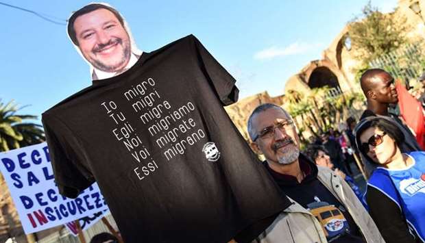 A man holds an effigy of Italian Interior minister and deputy PM, Matteo Salvini, reading in Italian the conjugation of the verb ,To Migrate, during a march of people, including employees of the country's social and reception centers and members of anti-racism associations, against the government's social politics, its recent decree restricting the right to asylum, and against racism.
