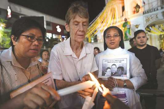 Australian nun Sister Patricia Fox lights a candle as she attends a prayer vigil for slain Catholic priests in front of Quiapo church in Manila earlier this year.