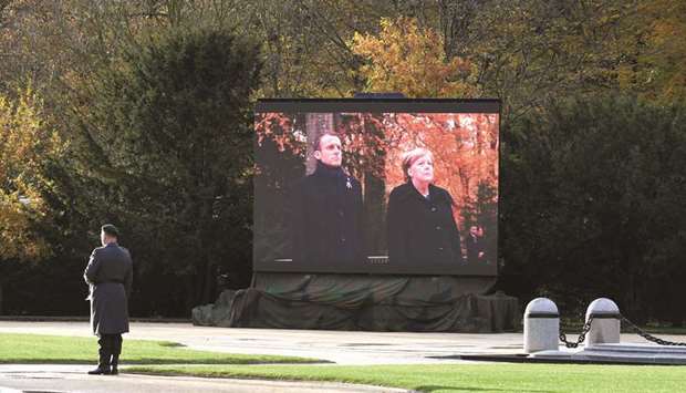 A German bugler stands ready near a big screen showing Merkel and Macron taking part in a French-German ceremony in the clearing of Rethondes (the Glade of the Armistice) in Compiegne, northern France, as part of commemorations marking the 100th anniversary of the November 11, 1918 armistice that ended World War I.