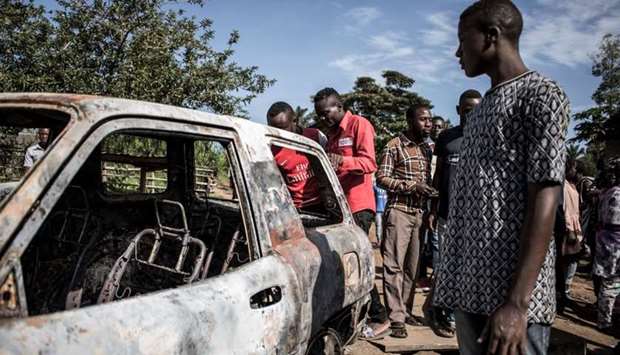 Congolese men look on at a car which has hit by a mortar, after an alleged attack by the Allied Democratic Forces (ADF) rebels.