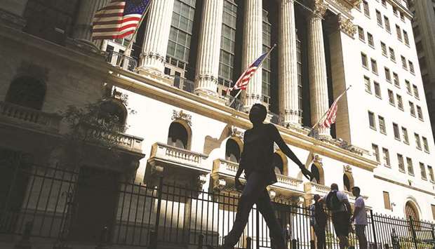 People walk by the New York Stock Exchange (file). US companies are warning about rising wages eating into profit margins, increasing investor worries that next yearu2019s expected drop in profit growth may be sharper than feared.