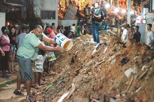 Residents work to clear rubble, as rescuers search for survivors in an area affected by a landslide due to heavy rains, in Niteroi, metropolitan region of Rio de Janeiro, Brazil.