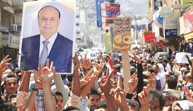 Protesters hold up a poster of Yemeni President Abd-Rabbu Mansour Hadi during a protest against the deteriorating economy in Taiz, Yemen.