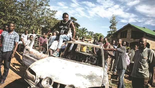 Congolese locals look at a car that was hit by a mortar after an alleged attack by rebels in Beni.