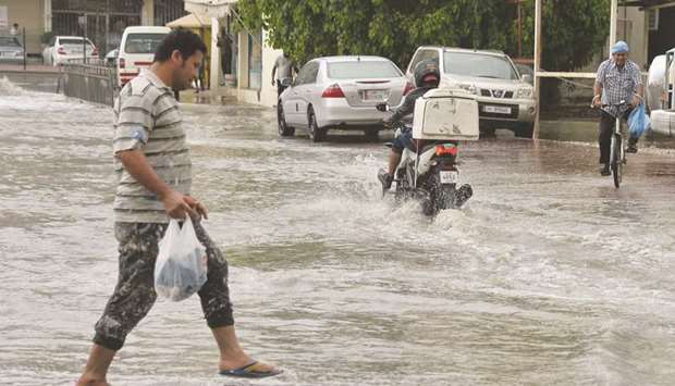 People make their way through a waterlogged road. PICTURE: Noushad Thekkayil