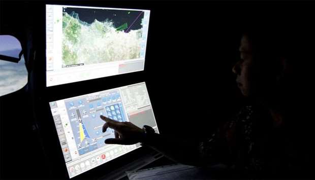A senior pilot of Lion Air Group points at the control computer during a routine practice session on a simulator at Angkasa Training Center near Jakarta
