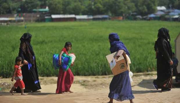 Rohingya refugees walk with belongings in Jamtoli refugee camp near Ukhia in Bangladesh.