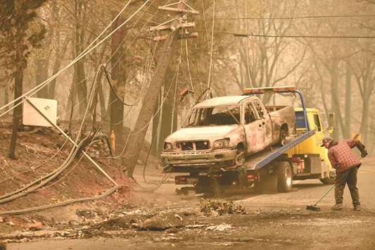 Crews begin removing abandoned vehicles from the streets after the Camp Fire tore through the area in Paradise.