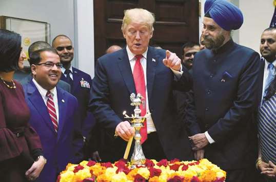 US President Donald Trump participates in the Diwali ceremonial lighting of the diya (lamp) as Indiau2019s ambassador Navtej Sarna looks on in the Roosevelt Room of the White House in Washington.