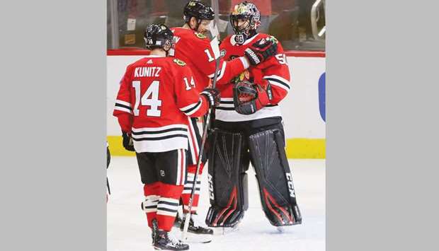 Chris Kunitz (left) and Artem Anisimov (centre) of the Chicago Blackhawks congratulate teammate Corey Crawford after a shut out win against the St Louis Blues. (AFP)
