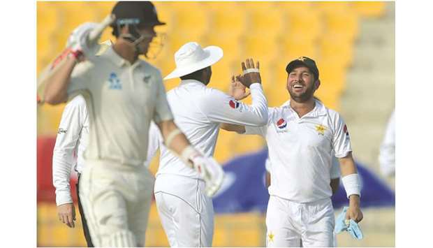 Pakistani spinner Yasir Shah (right) celebrates the wicket of New Zealandu2019s Ajaz Patel with a teammate on the first day of the first Test at the Sheikh Zayed International Cricket Stadium in Abu Dhabi yesterday. (AFP)