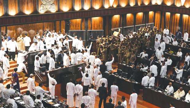 Sri Lankan police (right) gather to escort Parliament Speaker Karu Jayasuriya in the assembly hall as rival legislators (left) occupy the speakeru2019s seat in Colombo yesterday.