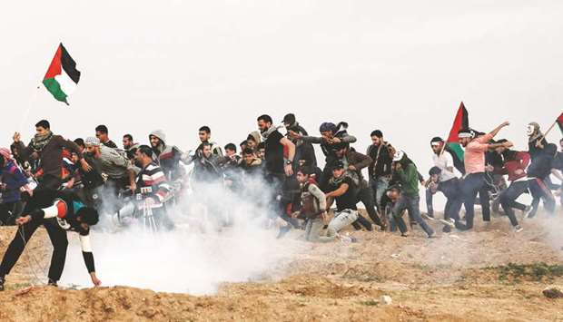 Palestinian demonstrators run for cover during a protest yesterday, on the eastern outskirts of Gaza City, near the border with Israel.