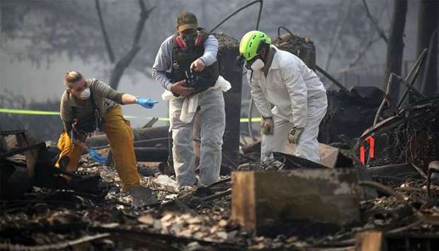Rescue workers search an area where they discovered suspected human remians in a home destroyed by the Camp Fire
