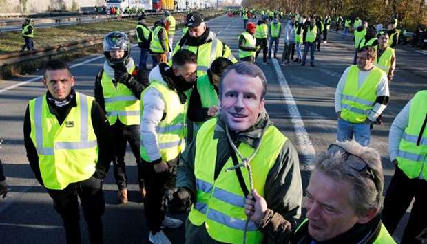 A man wears a mask with the likeness of French president Emmanuel Macron as people take part in the nationwide yellow vests demonstrations, a symbol of a French drivers' protest against higher fuel prices, yesterday in Haulchin, France