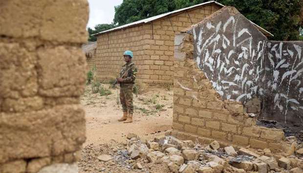 A United Nations peacekeeping soldier stands among houses destroyed by violence, in the abandoned village of Yade, Central African Republic