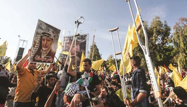 Supporters of exiled Palestinian politician and Fatah movementu2019s former security chief, Mohamed Dahlan, hold images of late Palestinian leader Yasser Arafat during a commemoration ceremony held on the occasion of the 14th anniversary of Arafatu2019s death, yesterday in Gaza City.