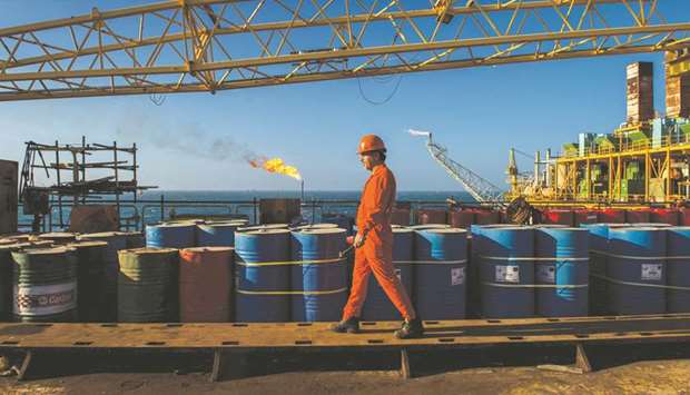 A worker passes stores of oil drums and gas flares while working aboard an offshore oil platform in the Salman Oil Field, operated by the National Iranian Offshore Oil Co, near Lavan island, Iran (file). China will start loading Iranian crude again in November after it halted purchases in October, according to people with knowledge of the matter.