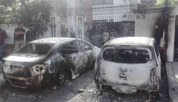 Pakistani security personnel stand next to burned out vehicles in front of the Chinese consulate after an attack in Karachi