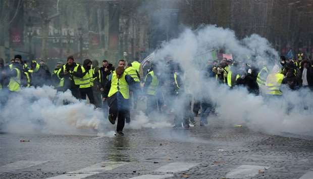 Yellow vests (Gilets jaunes) protestors demonstrate amid tear gas on the Champs Elysees in Paris