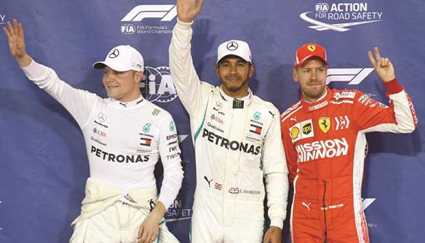 Mercedes driver Lewis Hamilton (centre) celebrates after taking the pole position in the qualifying session next to Ferrari driver Sebastian Vettel (right, third place) and Mercedes driver Valtteri Bottas (left, second place) at the Yas Marina circuit in Abu Dhabi yesterday. (AFP)