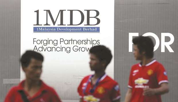 Men walk past a 1MDB billboard at the funds flagship Tun Razak Exchange development in Kuala Lumpur in this March 1, 2015 file photo. The furore surrounding Goldman Sachsu2019 role in raising money for the Malaysian state investment fund, known as 1MDB, has weighed on the banku2019s shares, which fell the most in seven years on November 12.